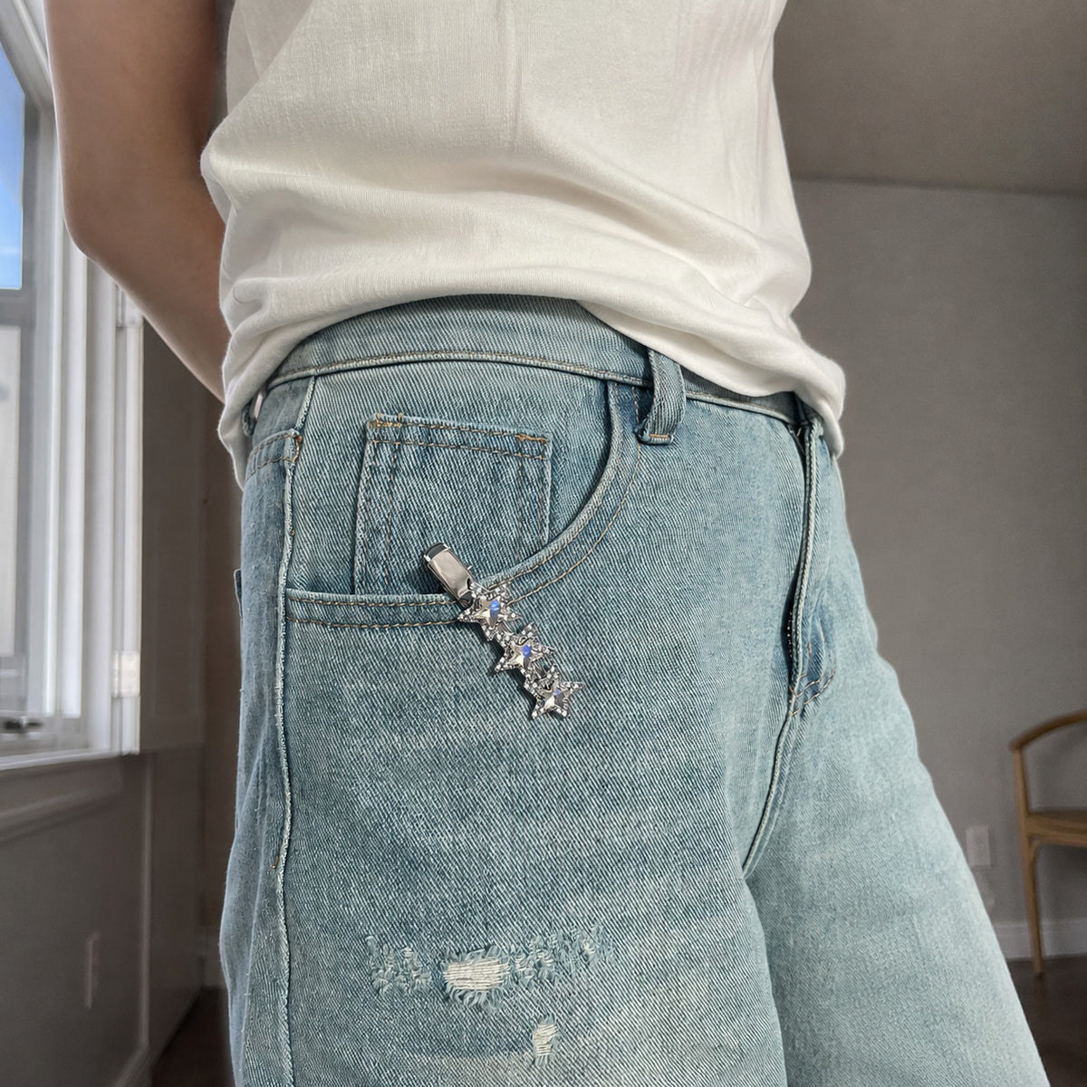 Celestial silver hair barrette attached to light-wash jeans as a decorative accessory with three shimmering gemstone stars.