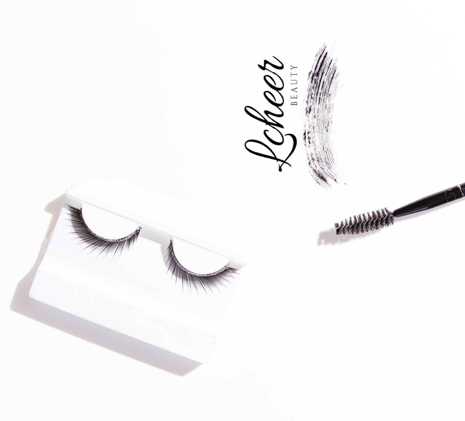 Minimal flat lay on white: tray-packed false lashes with LCHEER Beauty logo, a spoolie brush, and a black mascara swatch