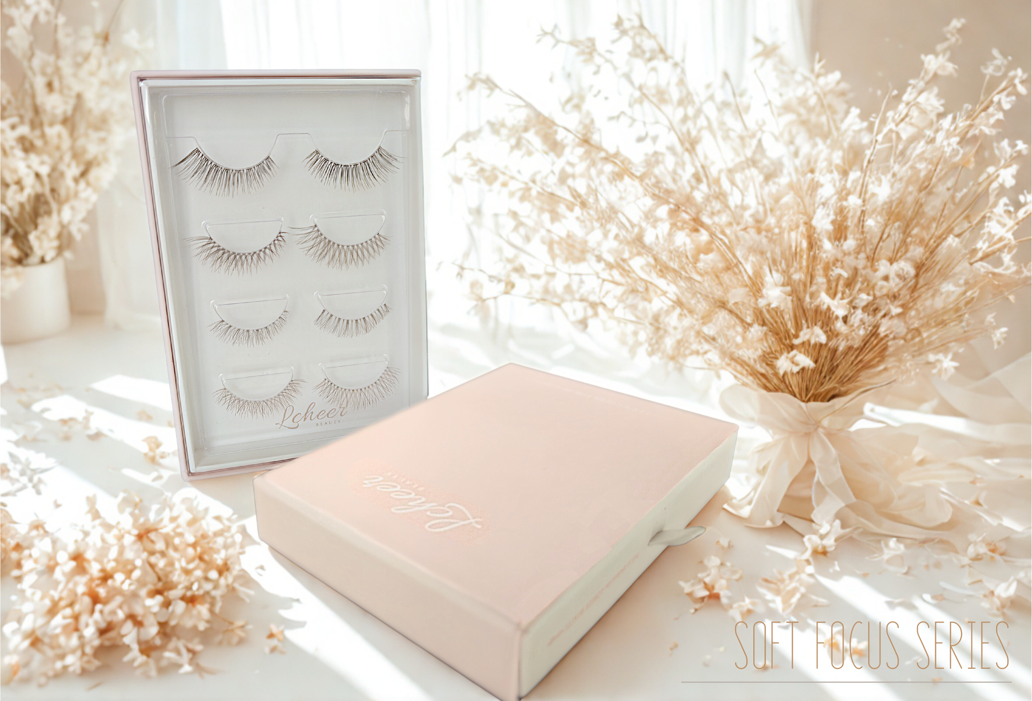 LCHEER Beauty multi-pair false lash set—clear display case and pink gift box on a white surface, accented by beige dried flowers in soft natural light