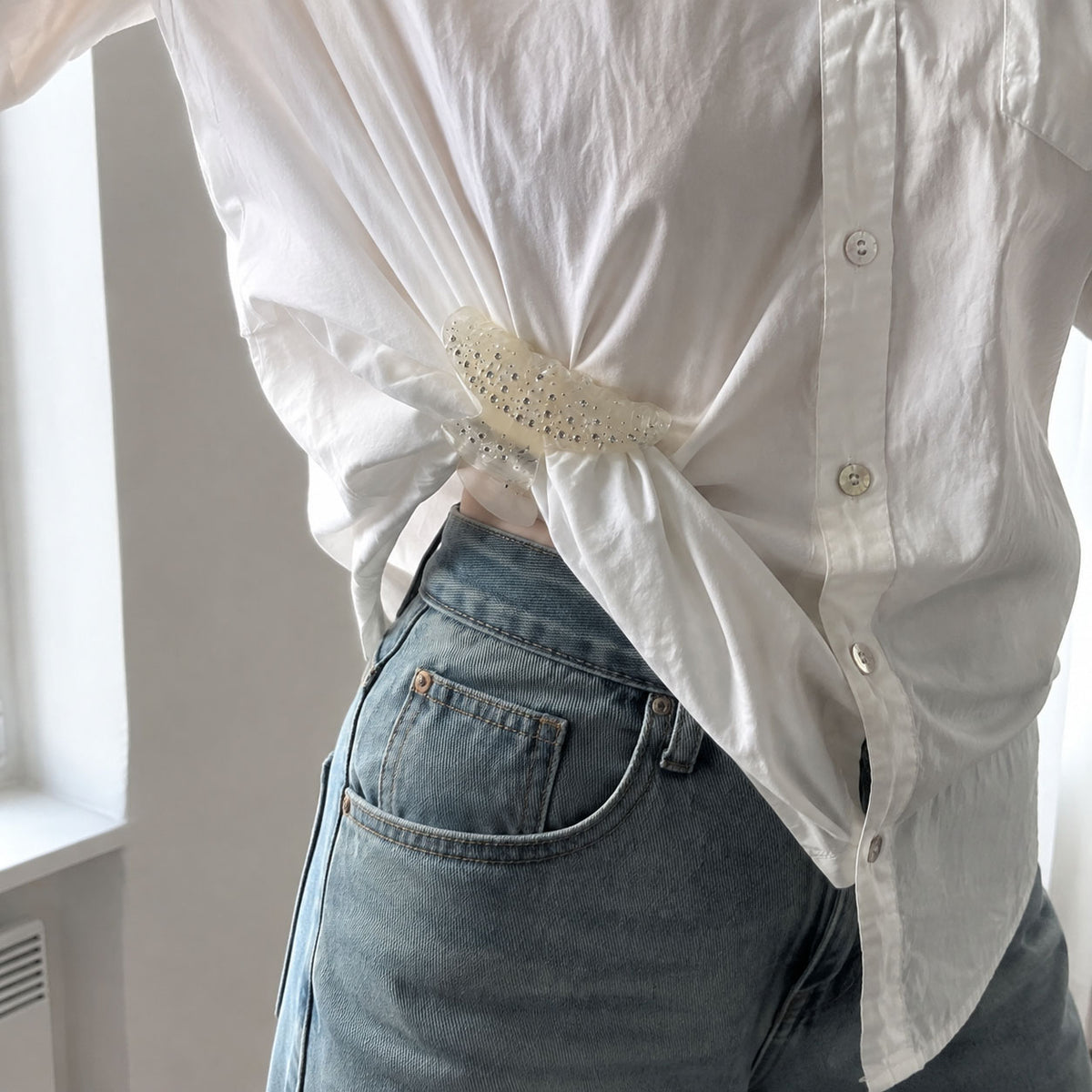 Decorative crystal hair clip fastening a knotted white shirt as a sparkling fashion accessory.
