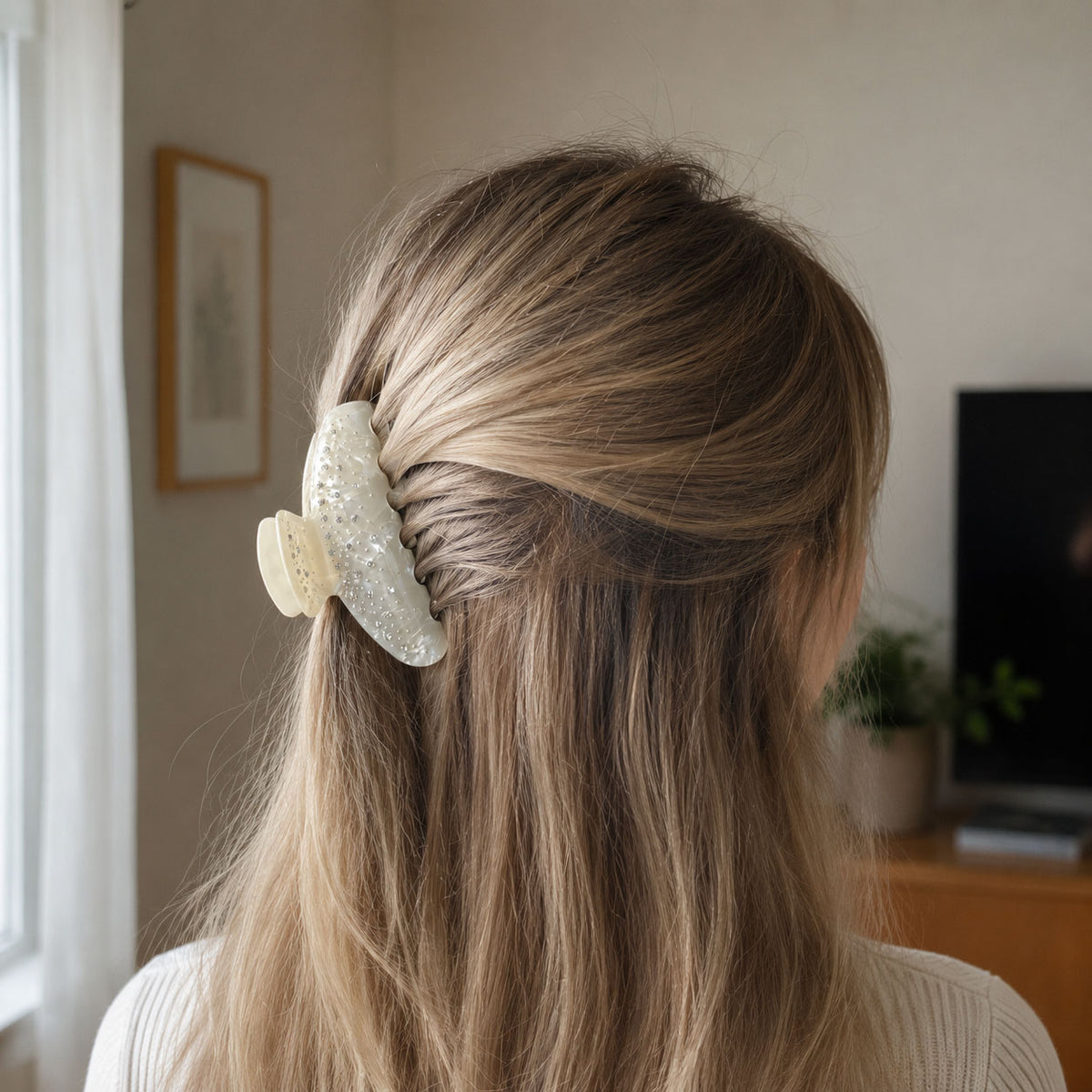 Large pearl white claw clip securing blonde hair in a relaxed half-up style with shimmering rhinestone details.